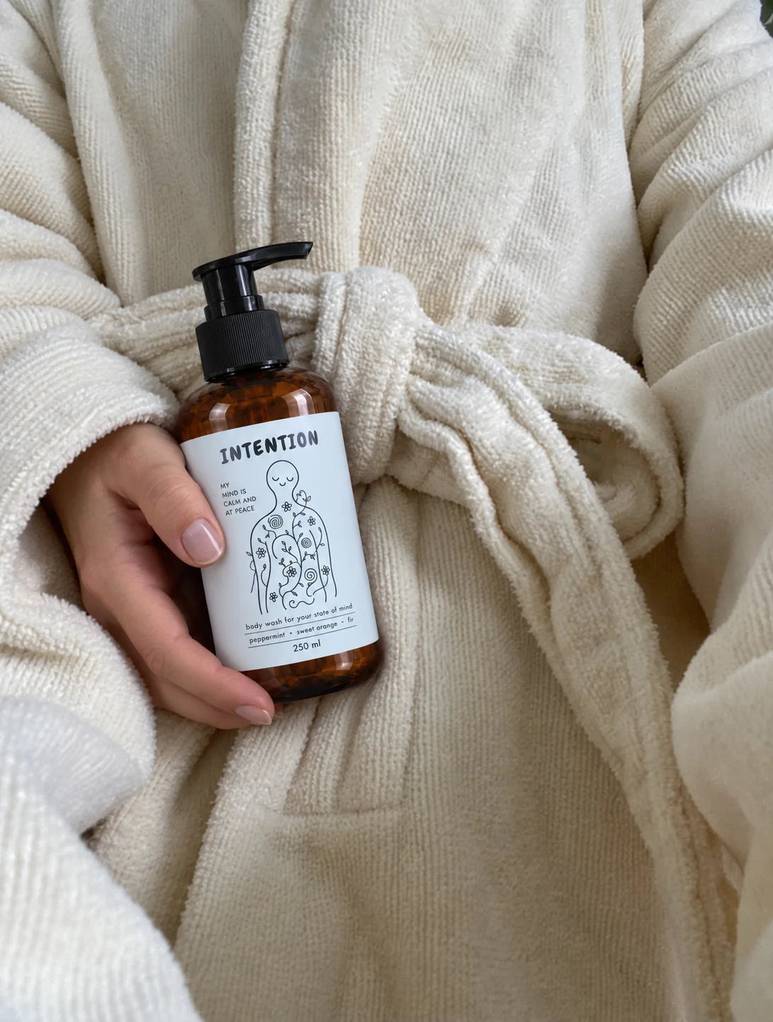 peace of mind body wash, held against a soft cream robe