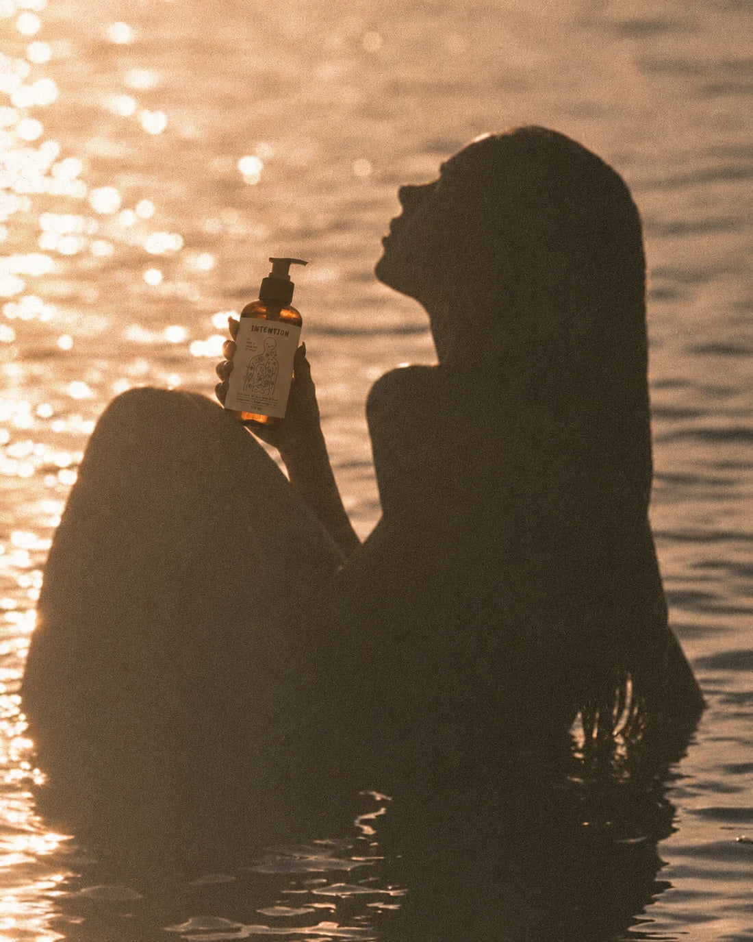 silhouette in golden water holding peace of mind body wash